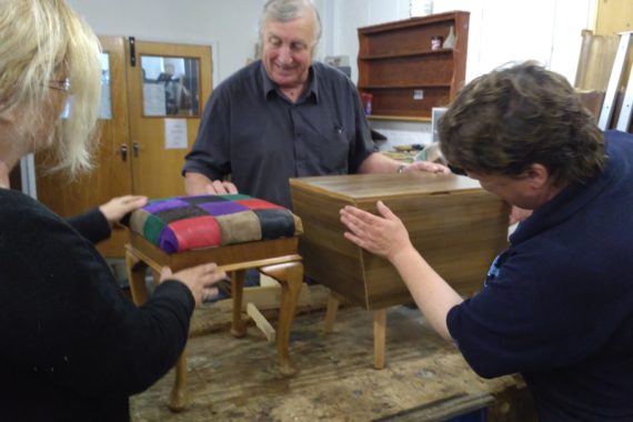 learners admire their finished furniture restoration